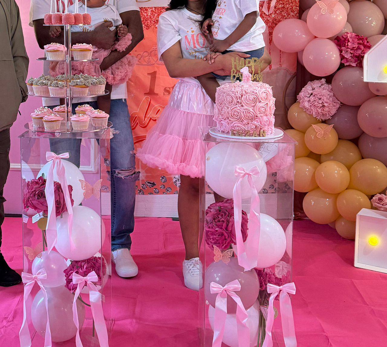 Full birthday party setup with a pink rosette cake, matching cupcake tower, and pink and gold balloon decor